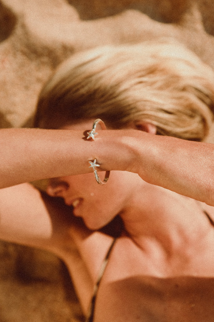 Elegant and durable sterling silver starfish bangle worn by the sea, Alula Collections Jewellery.